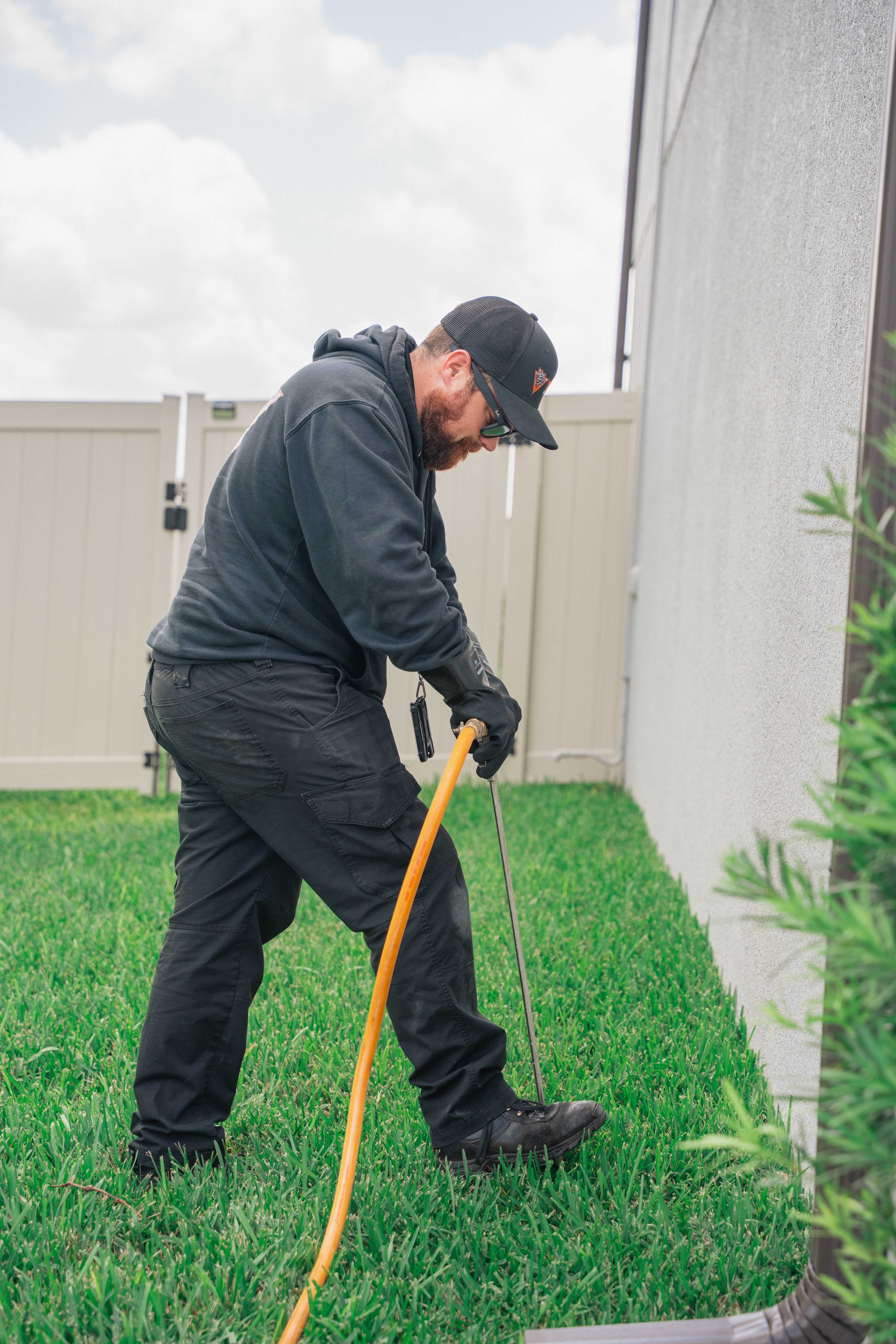 Pest control technician spraying along a Tampa home’s foundation